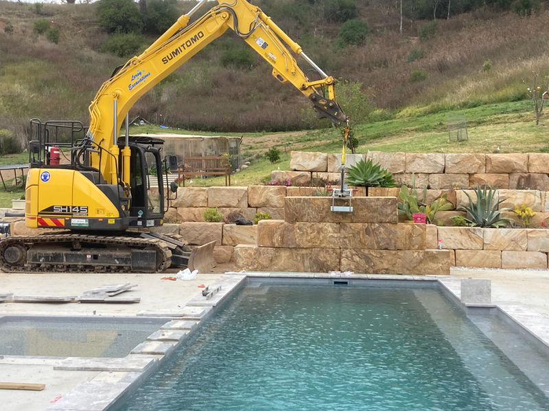 Excavator placing sandstone for retaining wall